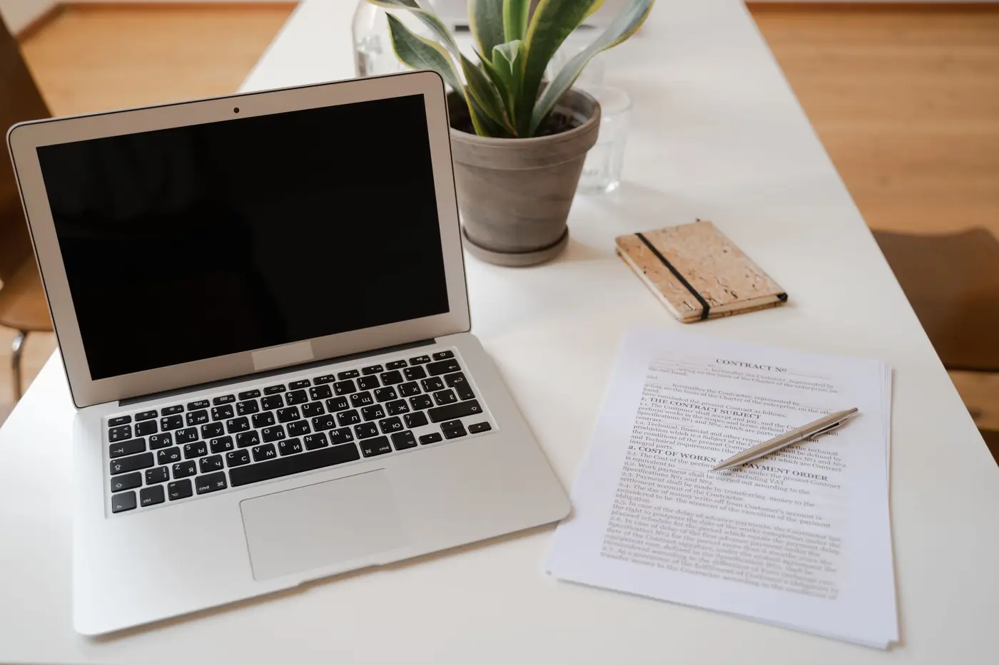Heller Besprechungstisch mit Laptop, Unterlagen und einer Pflanze